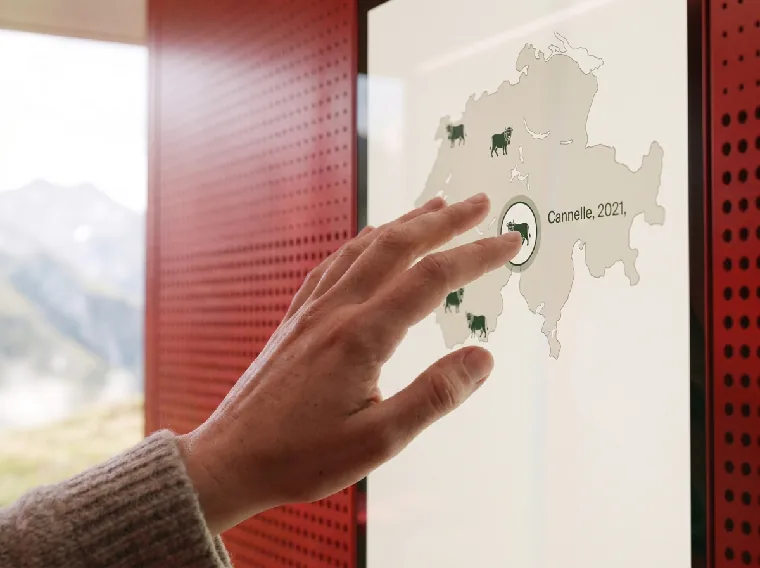 A hand touches a map of Switzerland on the pavilion touchscreen