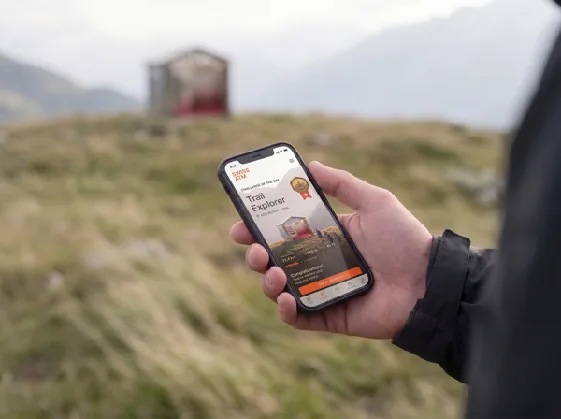 A phone shows the story of the product, with the pavilion blurred in the background